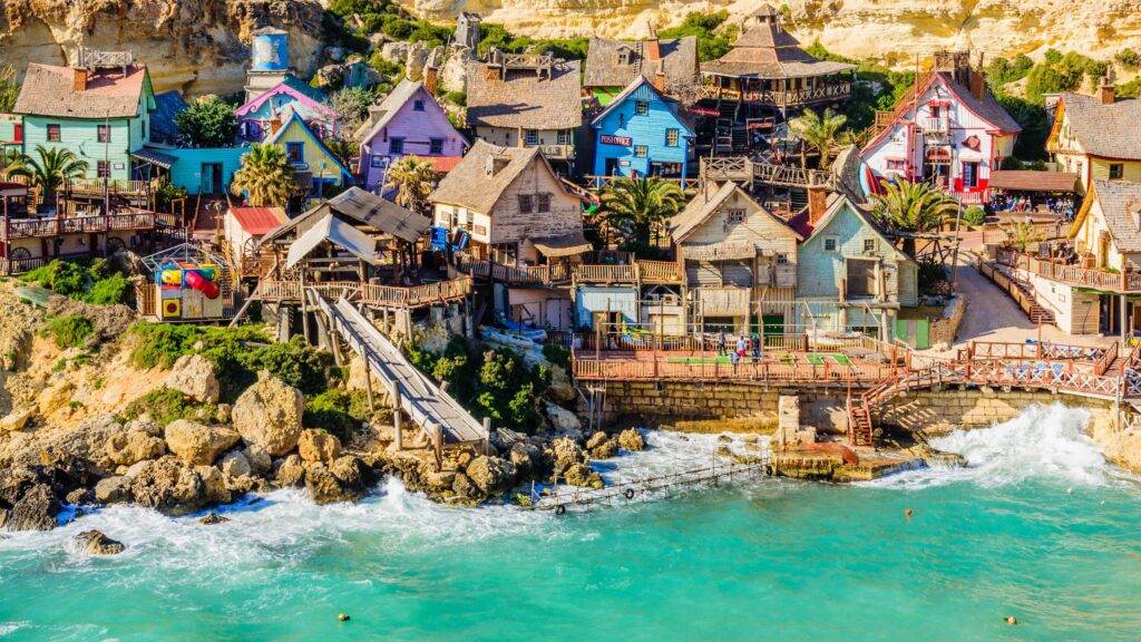Popeye Village, známa aj ako „Slum Village“, je čarovná dedinka postavená ako filmový set pre muzikál Popeye z roku 1980, ktorý sa natáčal na severozápadnom pobreží Malty v nádhernej zátoke Anchor Bay. Táto farebná drevená dedina pôvodne slúžila len na filmové účely, no po skončení natáčania bola zachovaná a premenená na obľúbenú turistickú atrakciu. Návštevníkov očarí nielen svojím autentickým dizajnom a malebným prostredím, ale aj jedinečnou atmosférou, ktorá vás vráti do čias klasickej filmovej rozprávky.